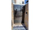 Black stainless steel entrance door with wave texture between natural stone walls