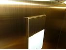 Detail of gold-coloured Oro HL stainless steel lift wall with precise edge folding and integrated panel