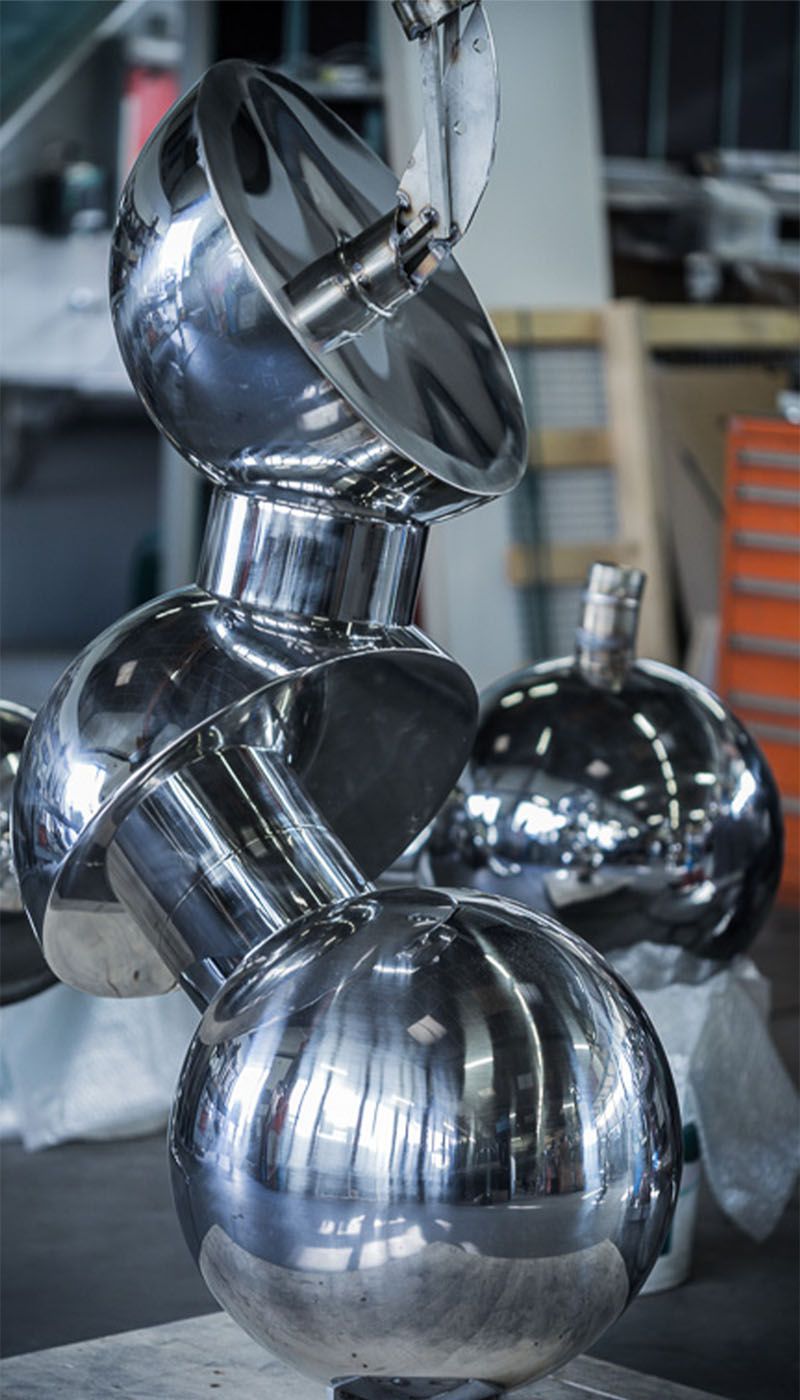 Polished stainless steel spheres and cylindrical elements in a workshop environment