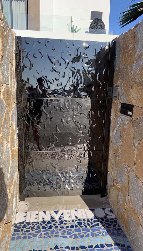Black stainless steel entrance door with wave texture between natural stone walls