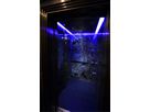 Lift cabin with natural stone rear wall and blue LED lighting within gold-coloured stainless steel frame