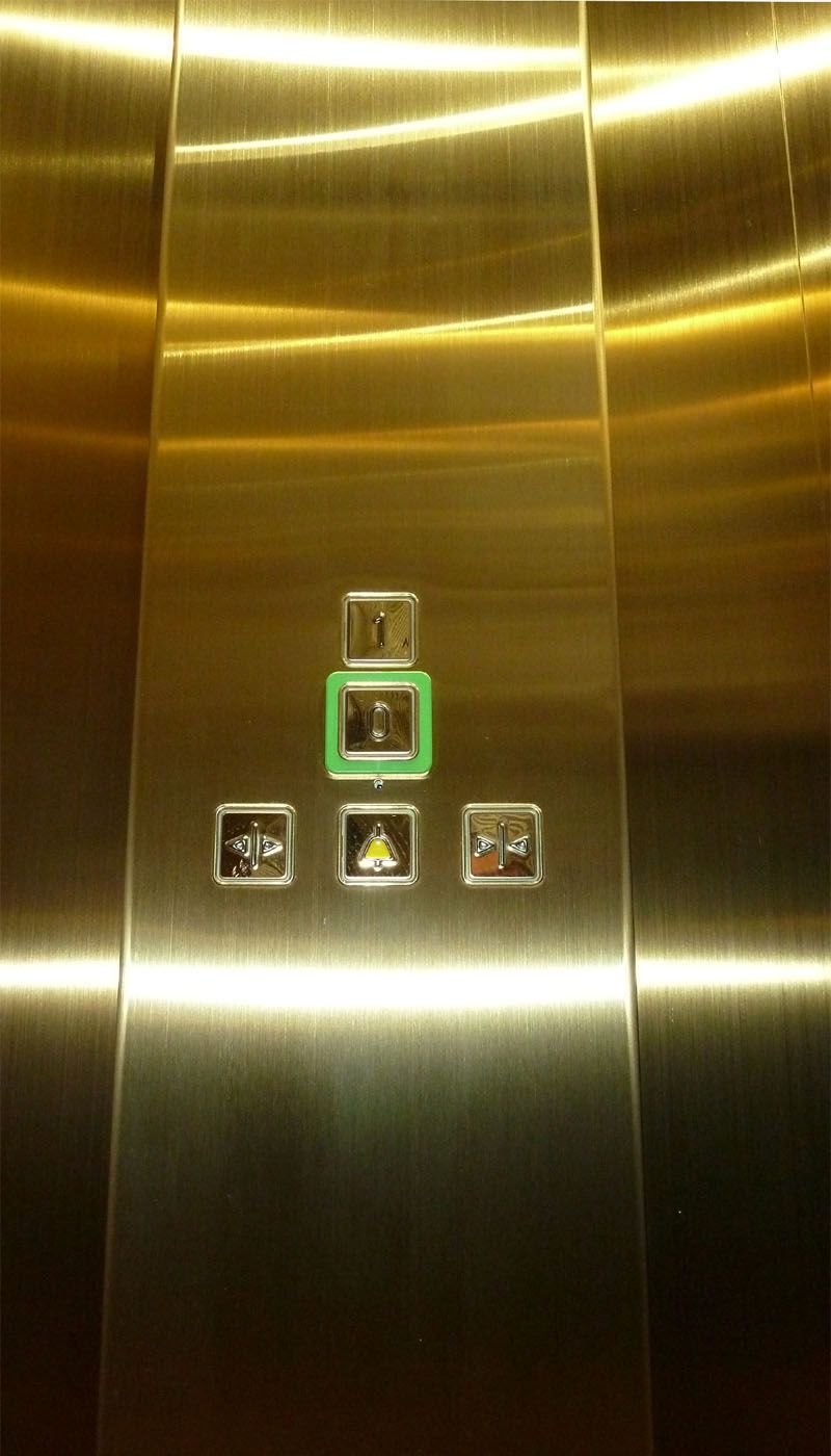 Control panel set into gold-coloured Oro HL stainless steel lift wall with illuminated buttons