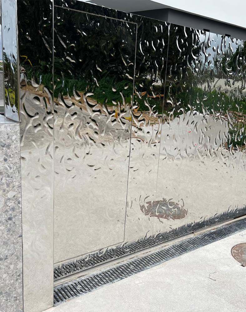 Detailansicht eines Einfahrtstores mit spiegelnder, wellenförmig strukturierter Edelstahloberfläche