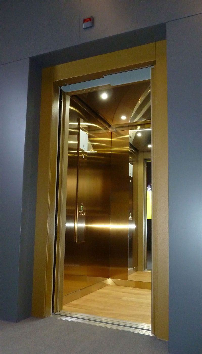 Open lift cabin with gold-coloured Oro HL stainless steel and matching door frame