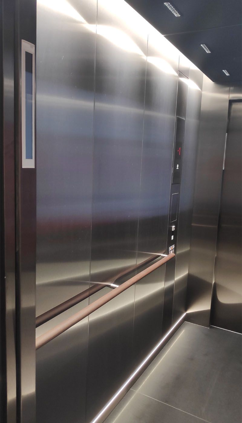 Seitenansicht des Multimedia-Aufzugs mit satinierten Edelstahlwänden und Handlauf