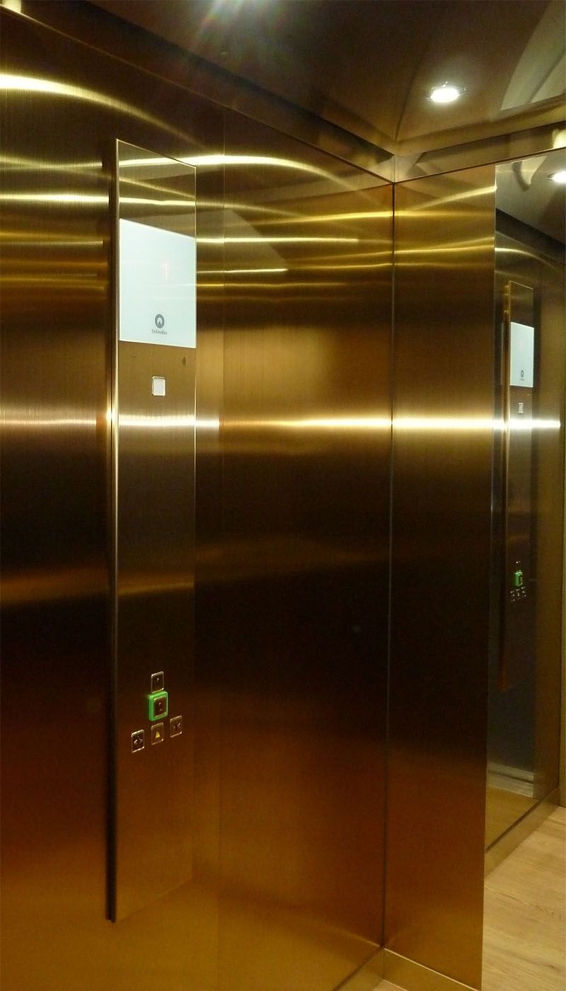 Lift cabin with gold-coloured Oro HL stainless steel walls and integrated display