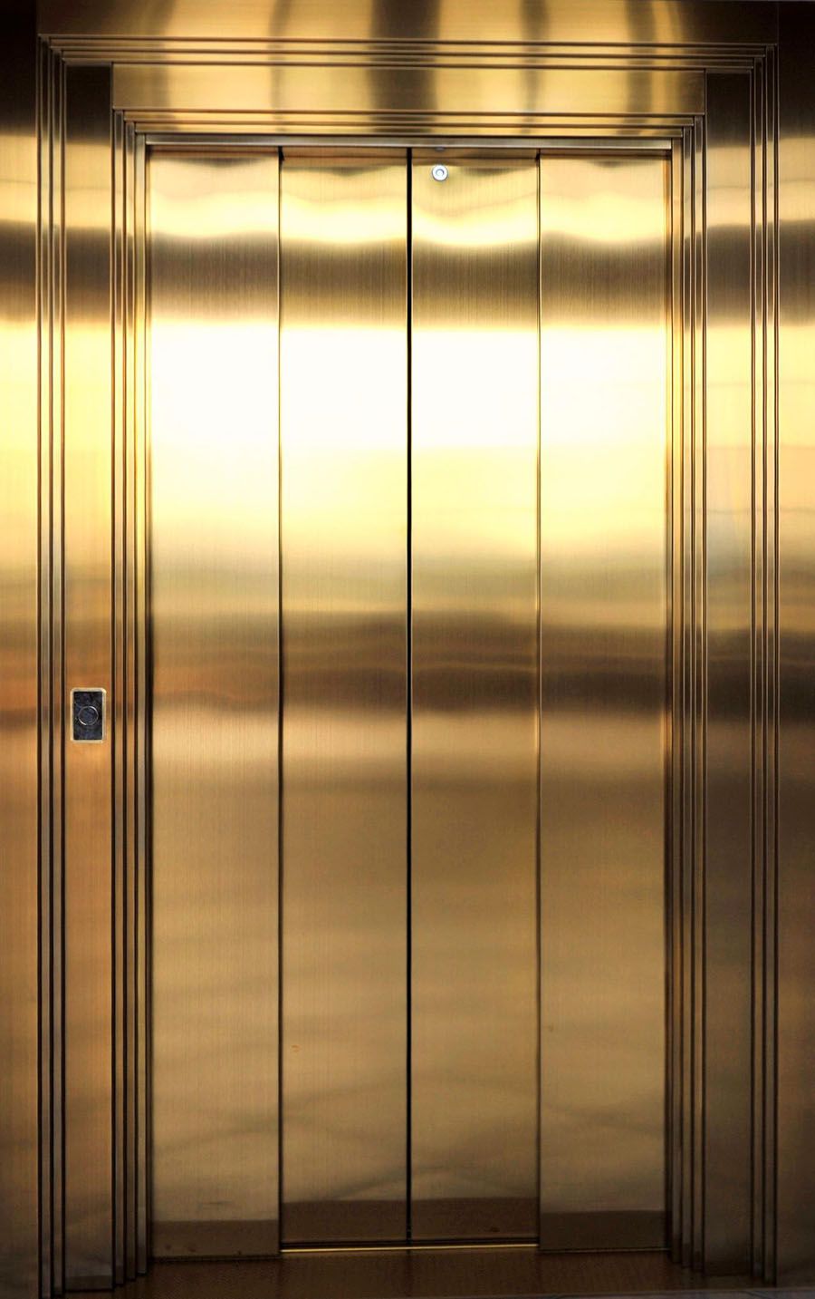 Closed gold-coloured stainless steel lift doors with vertical structure