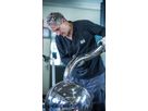 Person in workshop working on curved stainless steel tube attached to polished stainless steel sphere