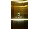 Control panel set into gold-coloured Oro HL stainless steel lift wall with illuminated buttons