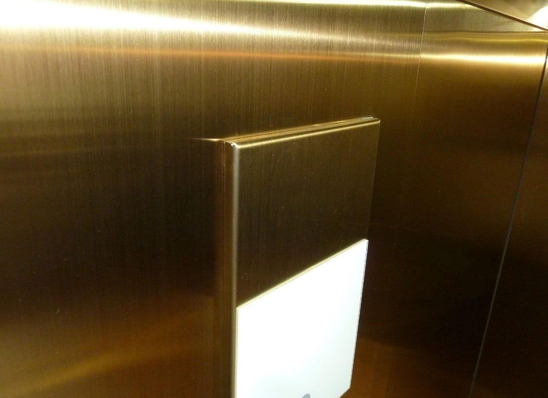 Detail of gold-coloured Oro HL stainless steel lift wall with precise edge folding and integrated panel