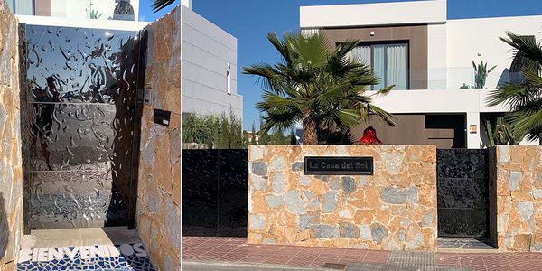 Modern villa with natural stone wall and black stainless steel entrance gate with wave texture
