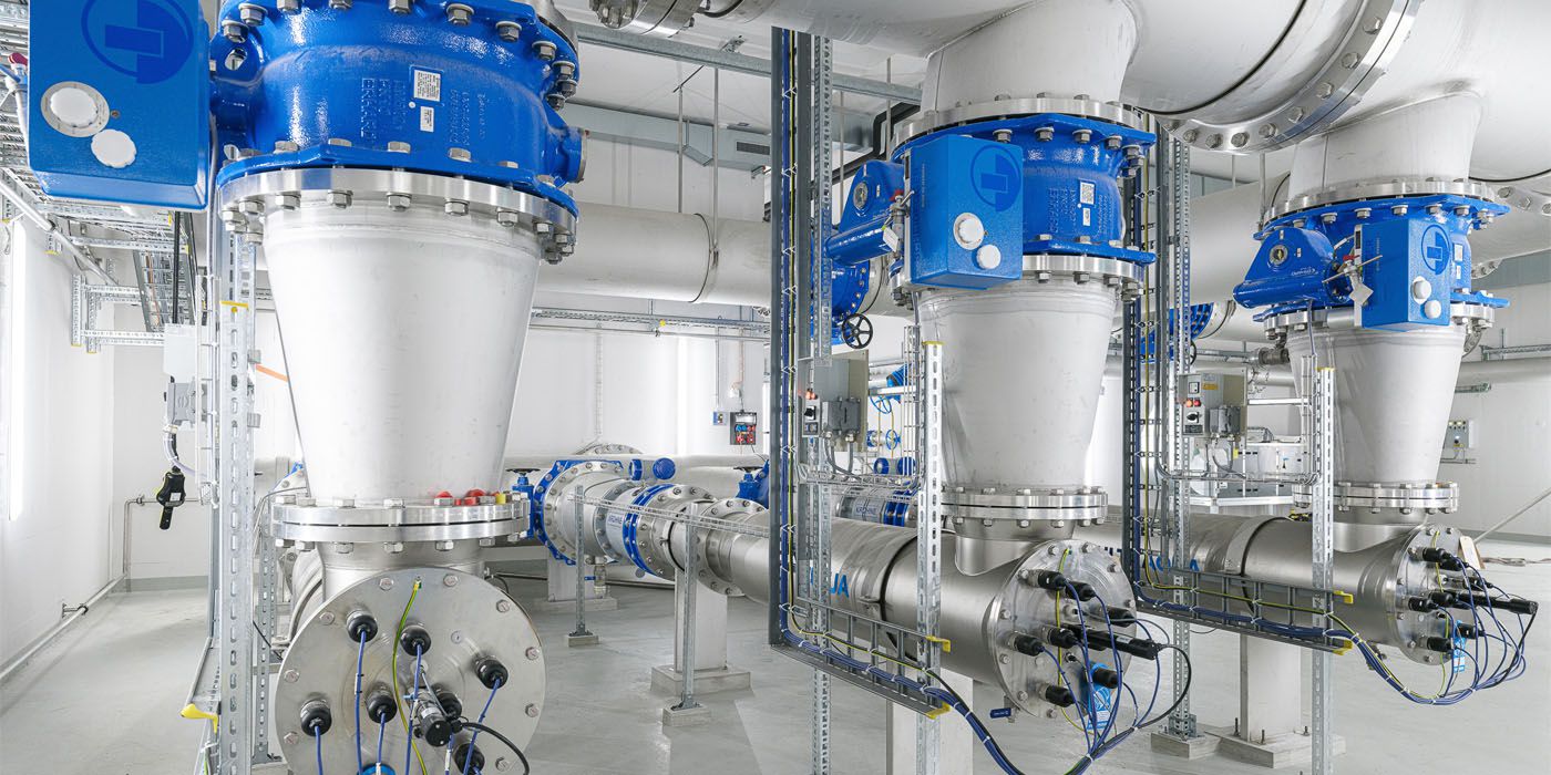Edelstahl-Rohrleitungen mit blauen Absperrarmaturen und Flanschverbindungen in einem Technikraum