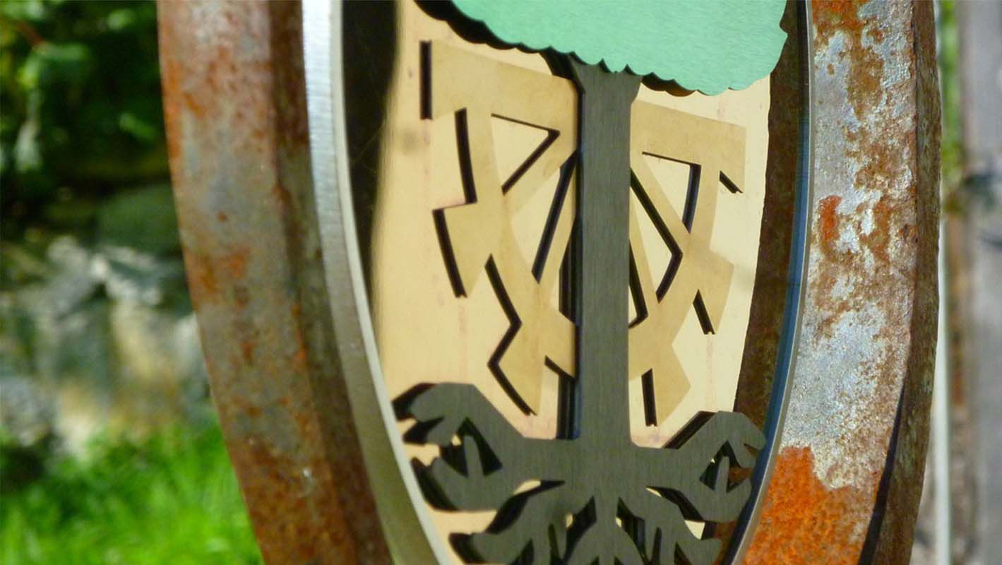 Close-up of the heraldic panel with laser-cut gold-coloured stainless steel elements and rusted metal ring