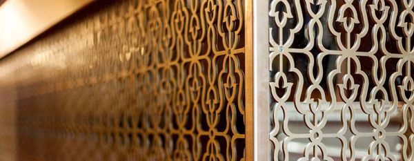 Bar cladding with ornamental perforated metal front and gold-coloured stainless steel surface behind